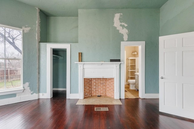 unfurnished living room with a tile fireplace, visible vents, dark wood finished floors, and baseboards