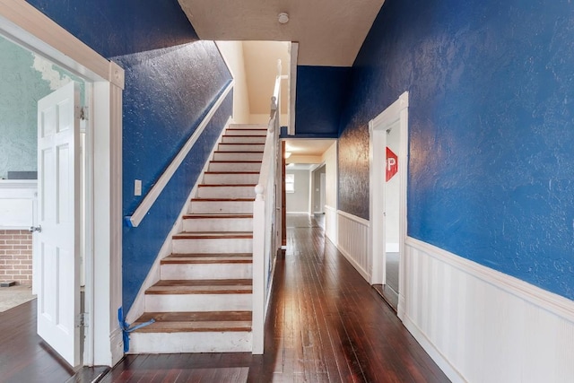 stairway featuring a wainscoted wall, a textured wall, and hardwood / wood-style floors