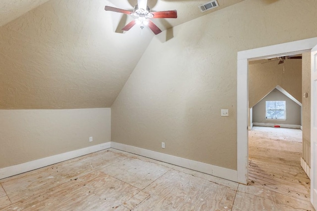 additional living space featuring a textured wall, visible vents, vaulted ceiling, and ceiling fan