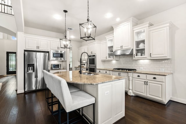 kitchen with an island with sink, white cabinetry, stainless steel appliances, and glass insert cabinets