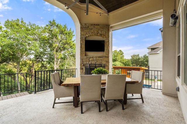 view of patio / terrace featuring outdoor dining area, an outdoor stone fireplace, and a ceiling fan