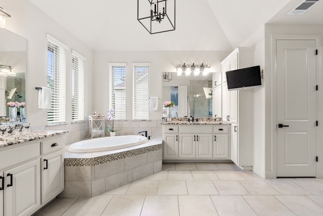 full bathroom with a garden tub, two vanities, visible vents, vaulted ceiling, and tile patterned floors