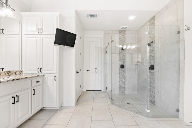 bathroom with a stall shower, vanity, and visible vents