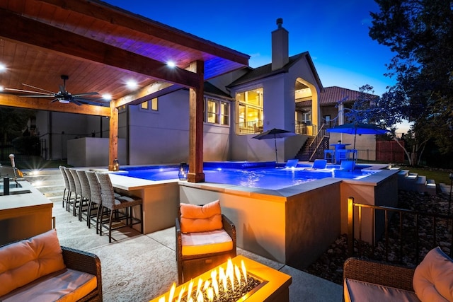 view of patio with ceiling fan, a fire pit, and outdoor dry bar