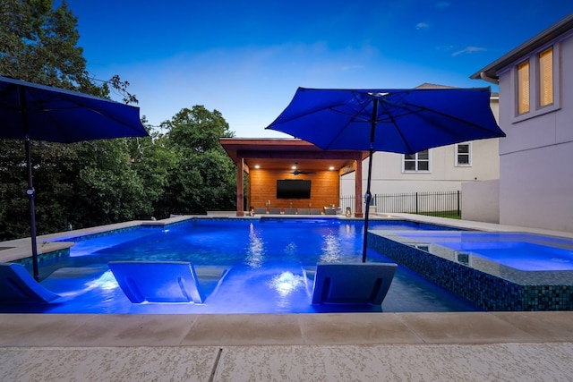 view of swimming pool with a ceiling fan, a pool with connected hot tub, and fence