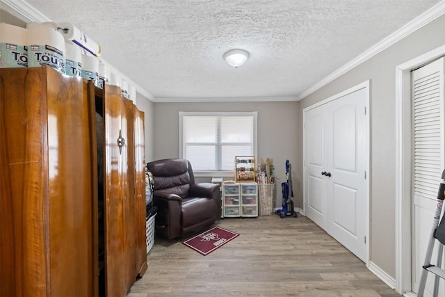 sitting room featuring baseboards, crown molding, a textured ceiling, and light wood finished floors