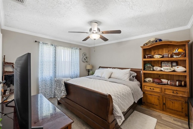 bedroom with a ceiling fan, light wood-style flooring, ornamental molding, and a textured ceiling