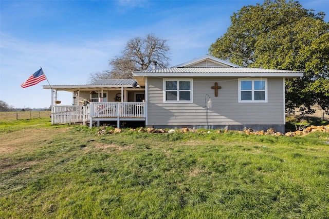 rear view of house with metal roof, a yard, and a deck