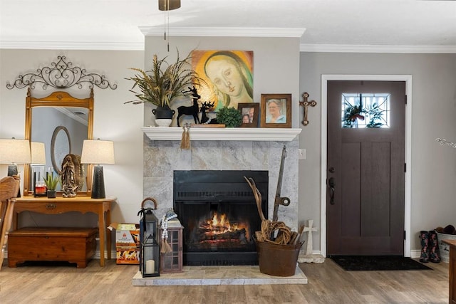 living area with a tile fireplace, crown molding, baseboards, and wood finished floors