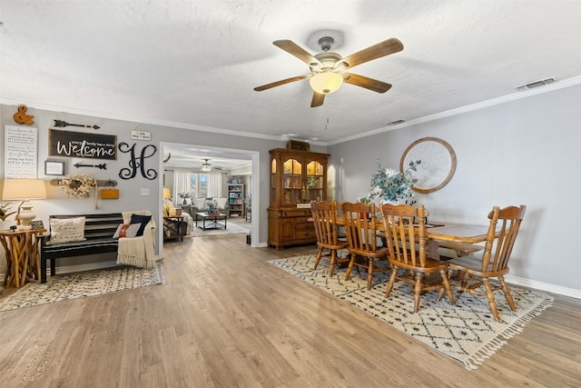 dining room with baseboards, visible vents, ornamental molding, wood finished floors, and a textured ceiling