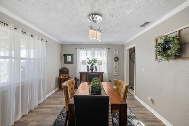 dining space featuring ornamental molding, visible vents, and wood finished floors