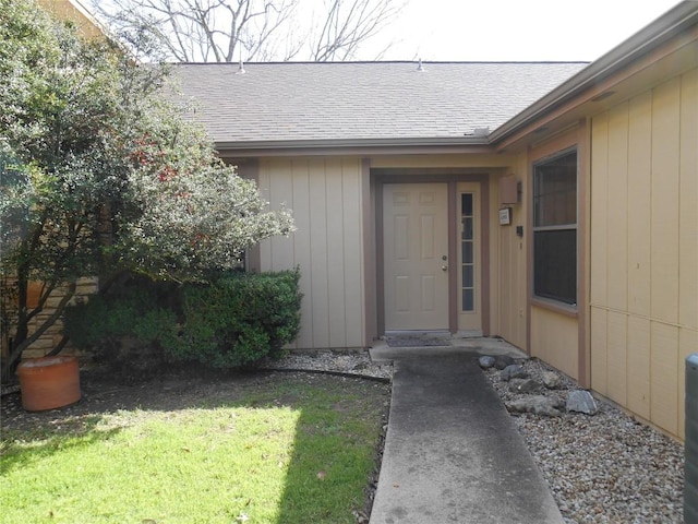 property entrance with a yard and roof with shingles