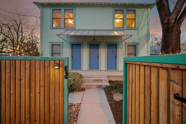 view of front of house featuring a fenced front yard, metal roof, and a porch