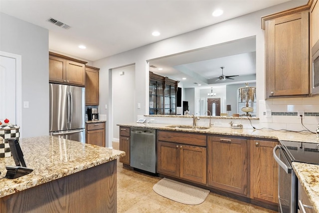 kitchen with stainless steel appliances, brown cabinets, a sink, and backsplash