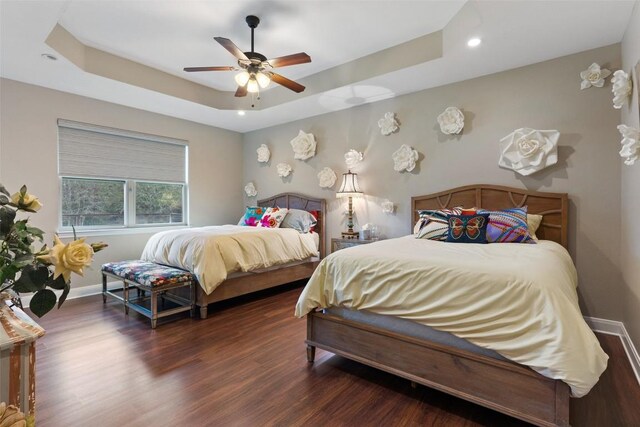 bedroom with dark wood-style flooring, recessed lighting, a raised ceiling, a ceiling fan, and baseboards