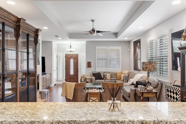 living area with dark wood-style floors, recessed lighting, a raised ceiling, and a ceiling fan