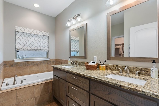 full bathroom with double vanity, a garden tub, and a sink