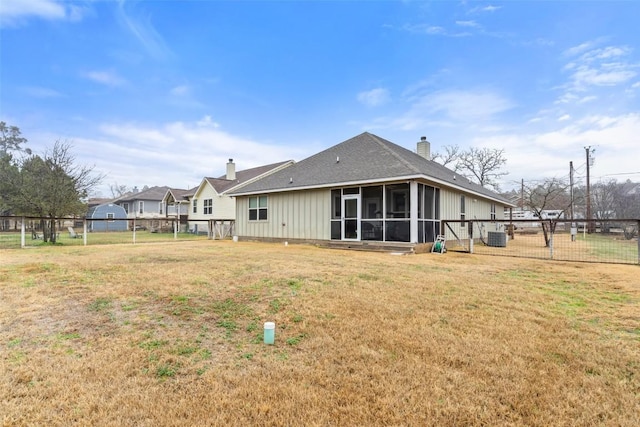 back of house featuring a sunroom, a fenced backyard, a chimney, and a yard