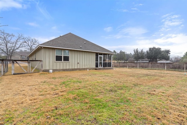 rear view of property featuring a lawn, board and batten siding, a sunroom, a gate, and a fenced backyard