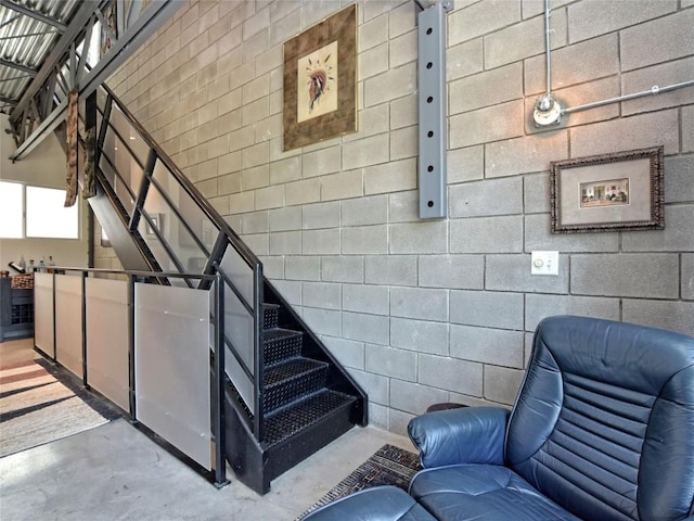 staircase with finished concrete flooring and concrete block wall