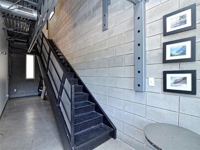 staircase featuring finished concrete flooring