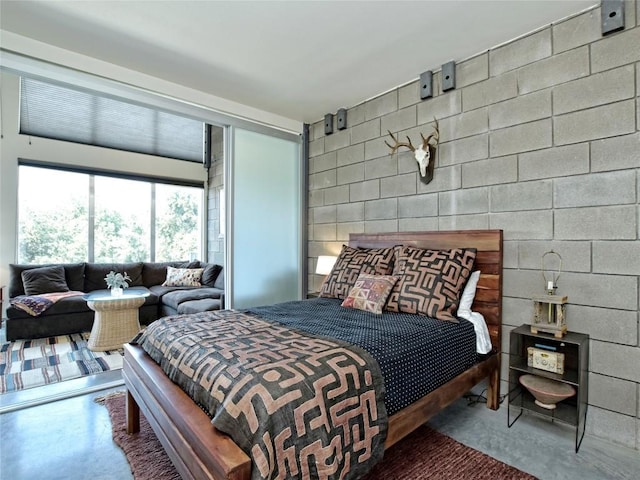 bedroom featuring finished concrete flooring and concrete block wall