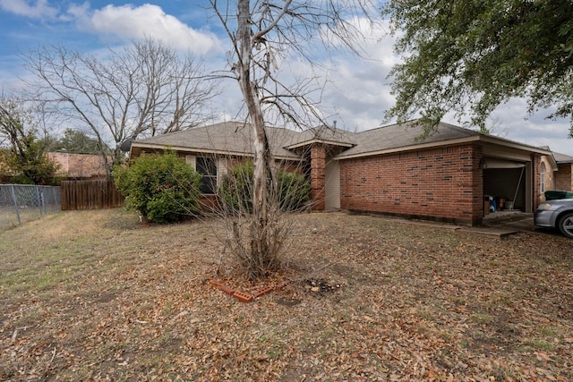 ranch-style house featuring a garage, brick siding, and fence