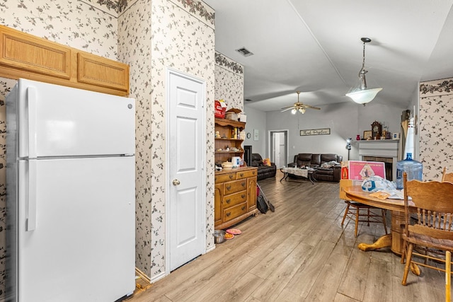 kitchen featuring a fireplace, visible vents, freestanding refrigerator, open floor plan, and light wood-type flooring