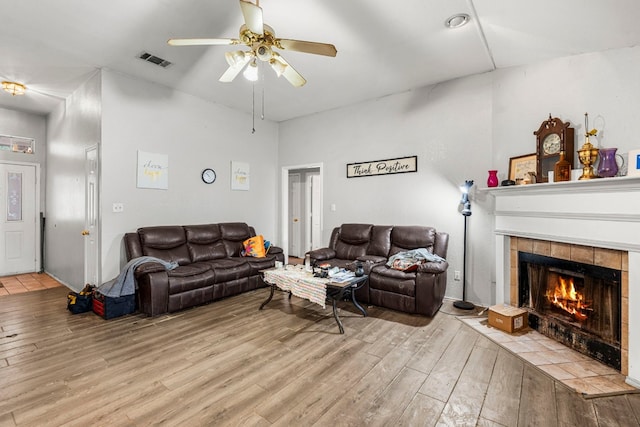 living area featuring ceiling fan, light wood-style flooring, a fireplace, and visible vents