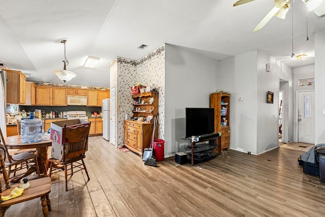 interior space featuring white appliances, visible vents, lofted ceiling, light countertops, and light wood-style floors