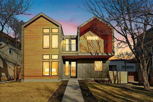 rear view of property featuring a yard and a balcony