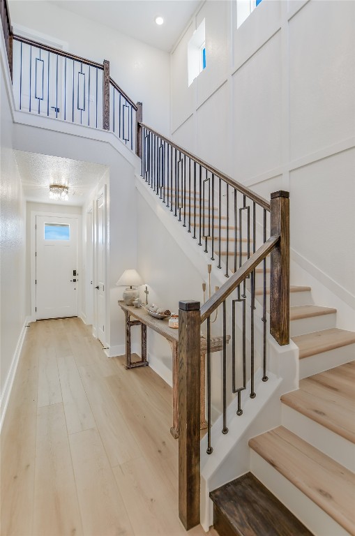 staircase featuring recessed lighting, baseboards, a high ceiling, and wood finished floors