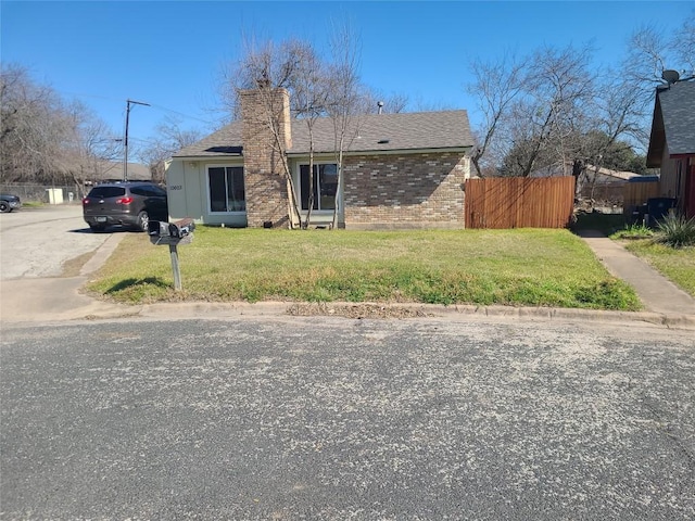 view of front of house featuring roof with shingles, a chimney, fence, and brick siding