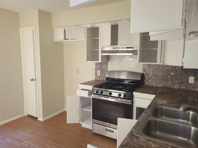 kitchen featuring dark countertops, stainless steel range with gas stovetop, white cabinetry, and a sink