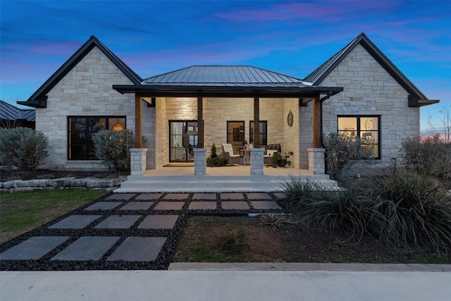 back of property at dusk with metal roof, a porch, and a standing seam roof