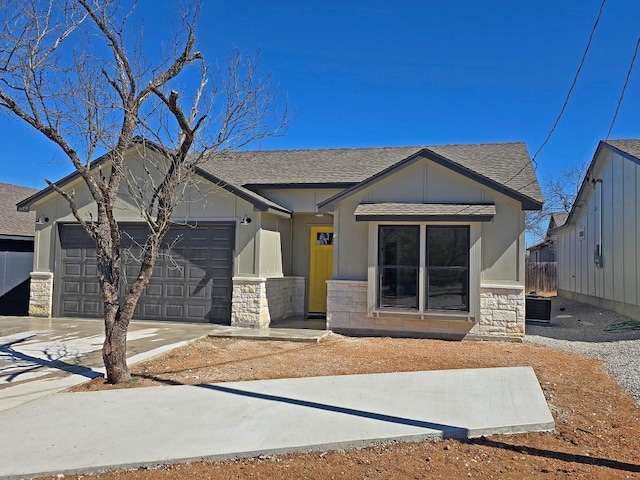 view of front of home with stone siding, a shingled roof, an attached garage, and driveway