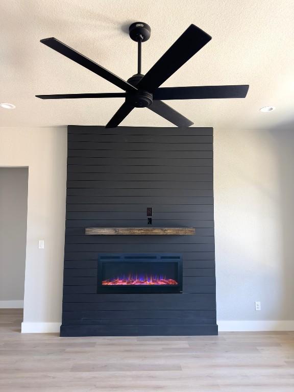 849 Cypress Ln, Cottonwood Shores, TX 78657 - detailed view of a large fireplace, a textured ceiling, wood finished floors, and ceiling fan