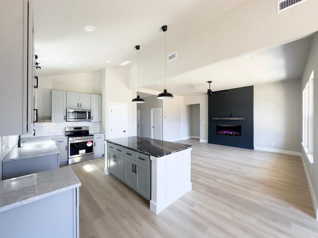 849 Cypress Ln, Cottonwood Shores, TX 78657 - kitchen featuring stainless steel appliances, a ceiling fan, a kitchen island, light wood-style flooring, and a large fireplace