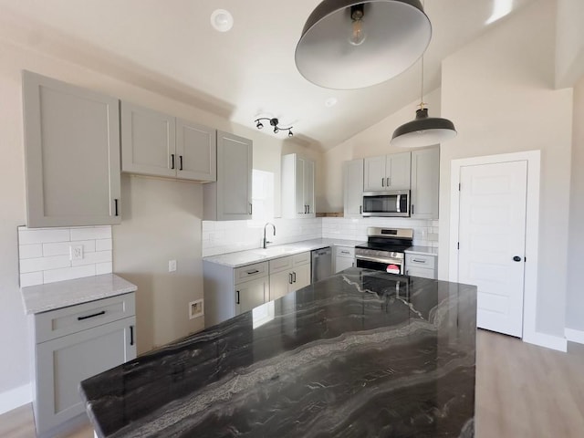 849 Cypress Ln, Cottonwood Shores, TX 78657 - kitchen featuring appliances with stainless steel finishes, light stone countertops, vaulted ceiling, gray cabinetry, and backsplash