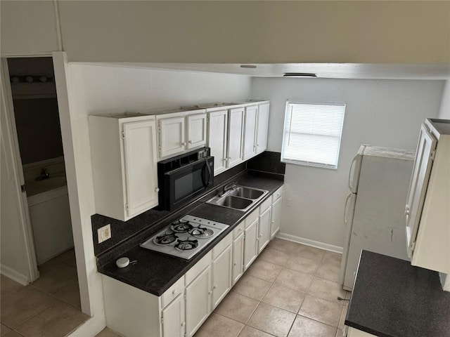 kitchen featuring white gas stovetop, black microwave, dark countertops, and white cabinets