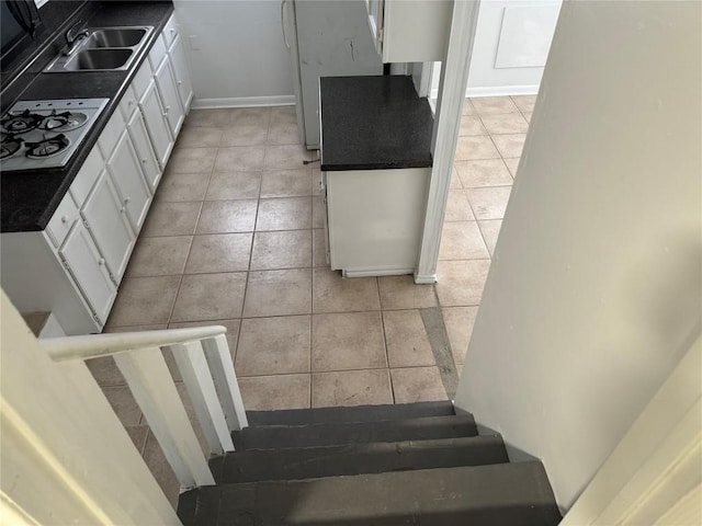 kitchen featuring white gas stovetop, white cabinetry, dark countertops, and light tile patterned flooring
