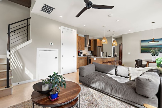 living room with visible vents, a ceiling fan, stairs, light wood-style floors, and recessed lighting