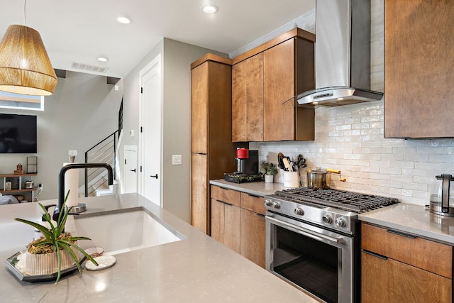 kitchen with stainless steel gas stove, visible vents, a sink, wall chimney range hood, and backsplash