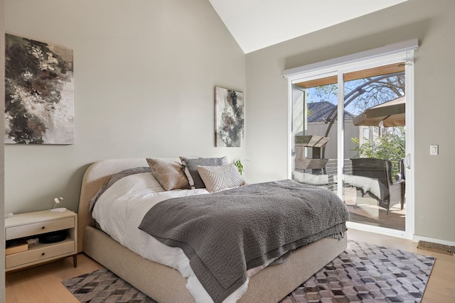 bedroom featuring access to exterior, lofted ceiling, and wood finished floors