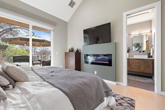 bedroom with visible vents, a glass covered fireplace, access to outside, vaulted ceiling, and a sink