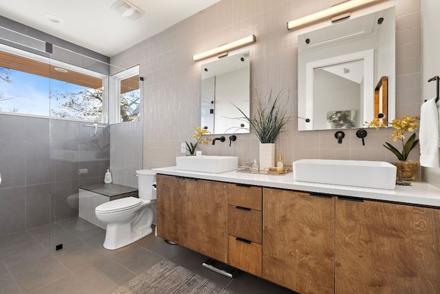 full bath featuring a sink, tile walls, toilet, and tile patterned floors