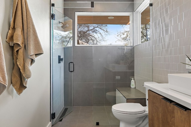 bathroom featuring a stall shower, tile walls, toilet, and tile patterned floors