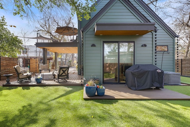 rear view of property with a balcony, central AC, fence, a yard, and a wooden deck