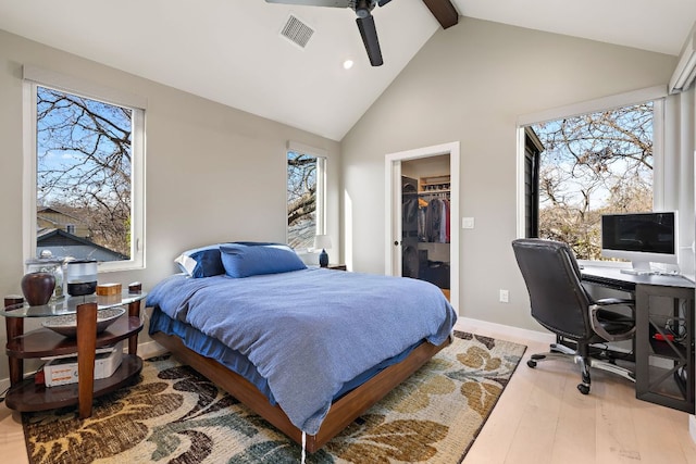 bedroom with high vaulted ceiling, wood finished floors, visible vents, beam ceiling, and a walk in closet