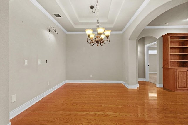 unfurnished room featuring light wood finished floors, visible vents, arched walkways, baseboards, and a tray ceiling